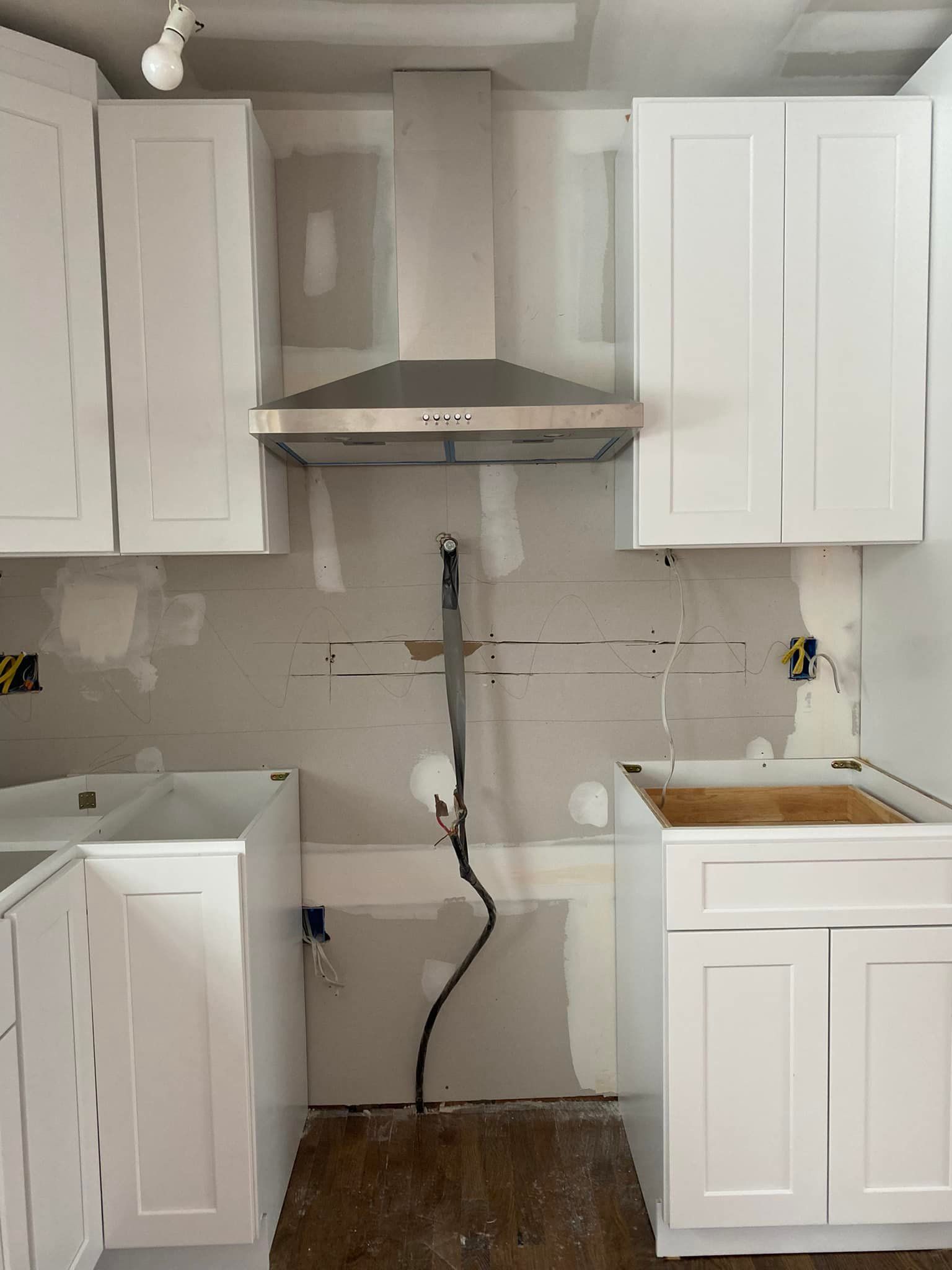 A kitchen with white cabinets and a stainless steel hood