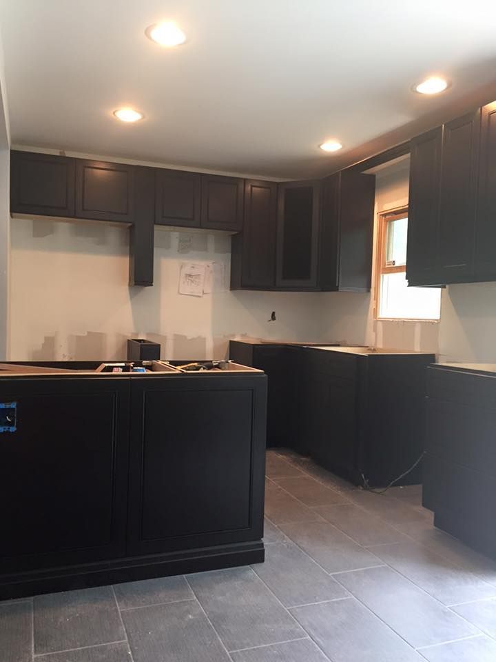 An empty kitchen with black cabinets and a window