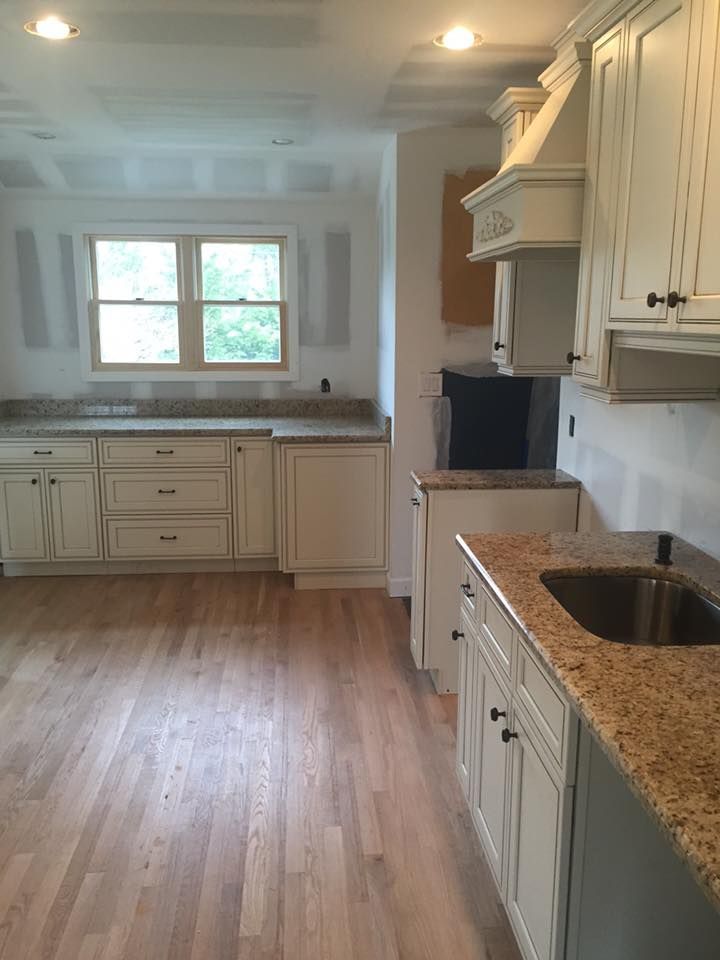 A kitchen with white cabinets , granite counter tops , and a sink.