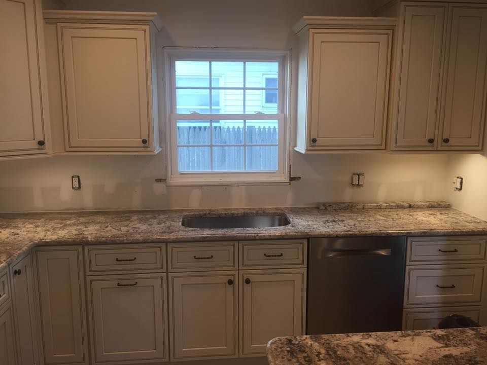 A kitchen with white cabinets , granite counter tops , a sink , and a window.