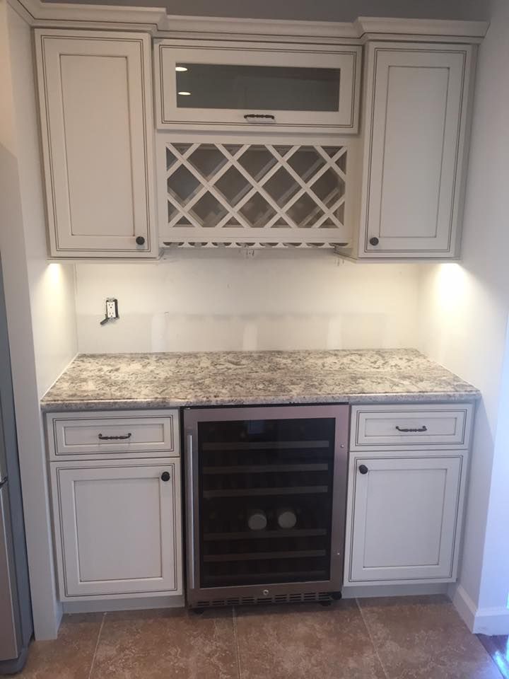 A kitchen with white cabinets and a wine cooler.