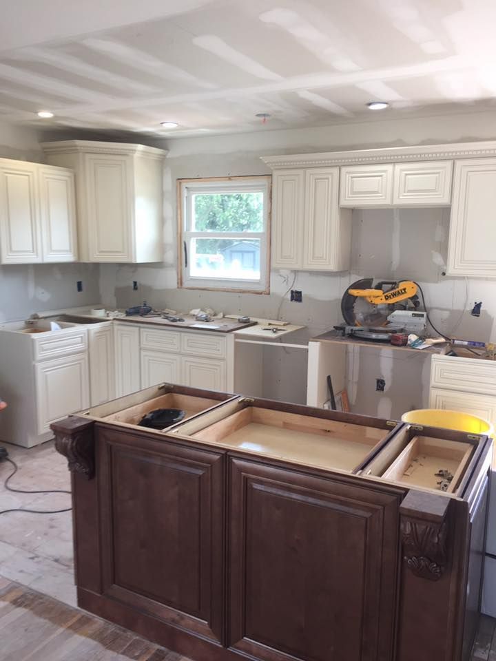 A kitchen under construction with white cabinets and a large island.