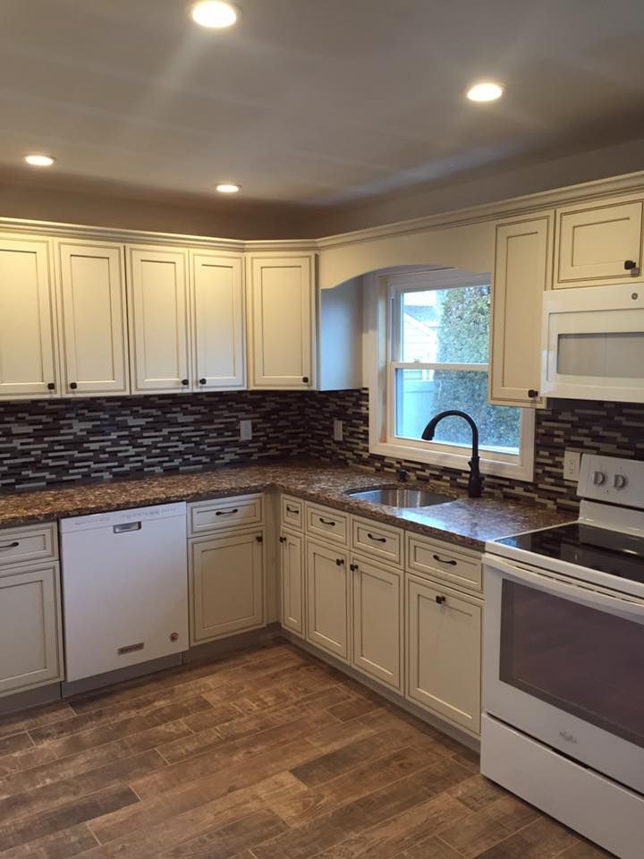 A kitchen with white cabinets , granite counter tops , a stove and a sink.