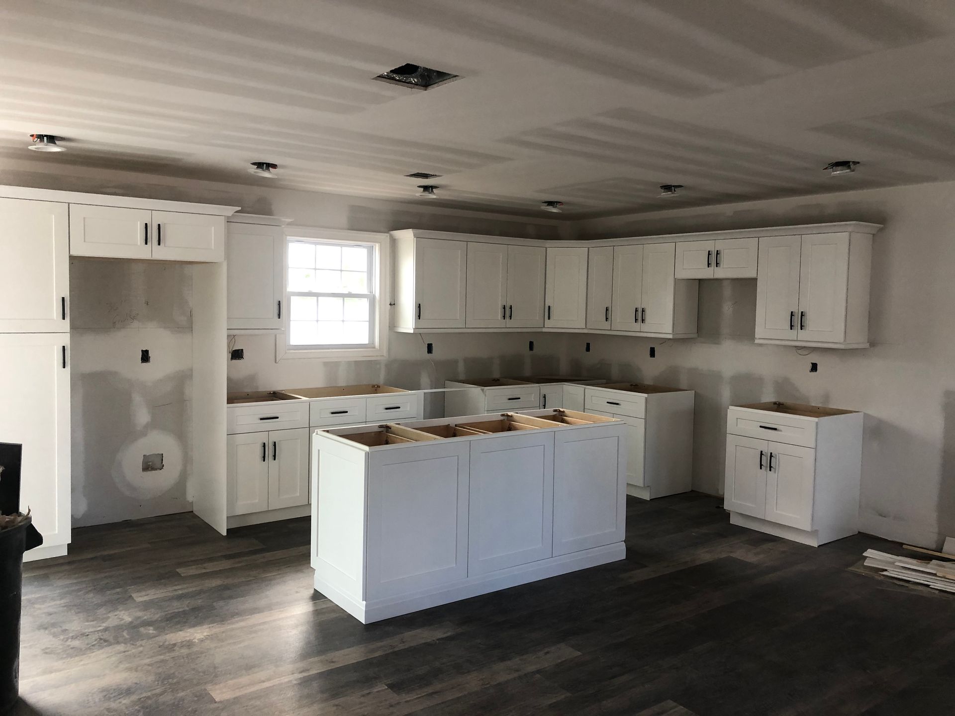 A kitchen with white cabinets and a large island in the middle