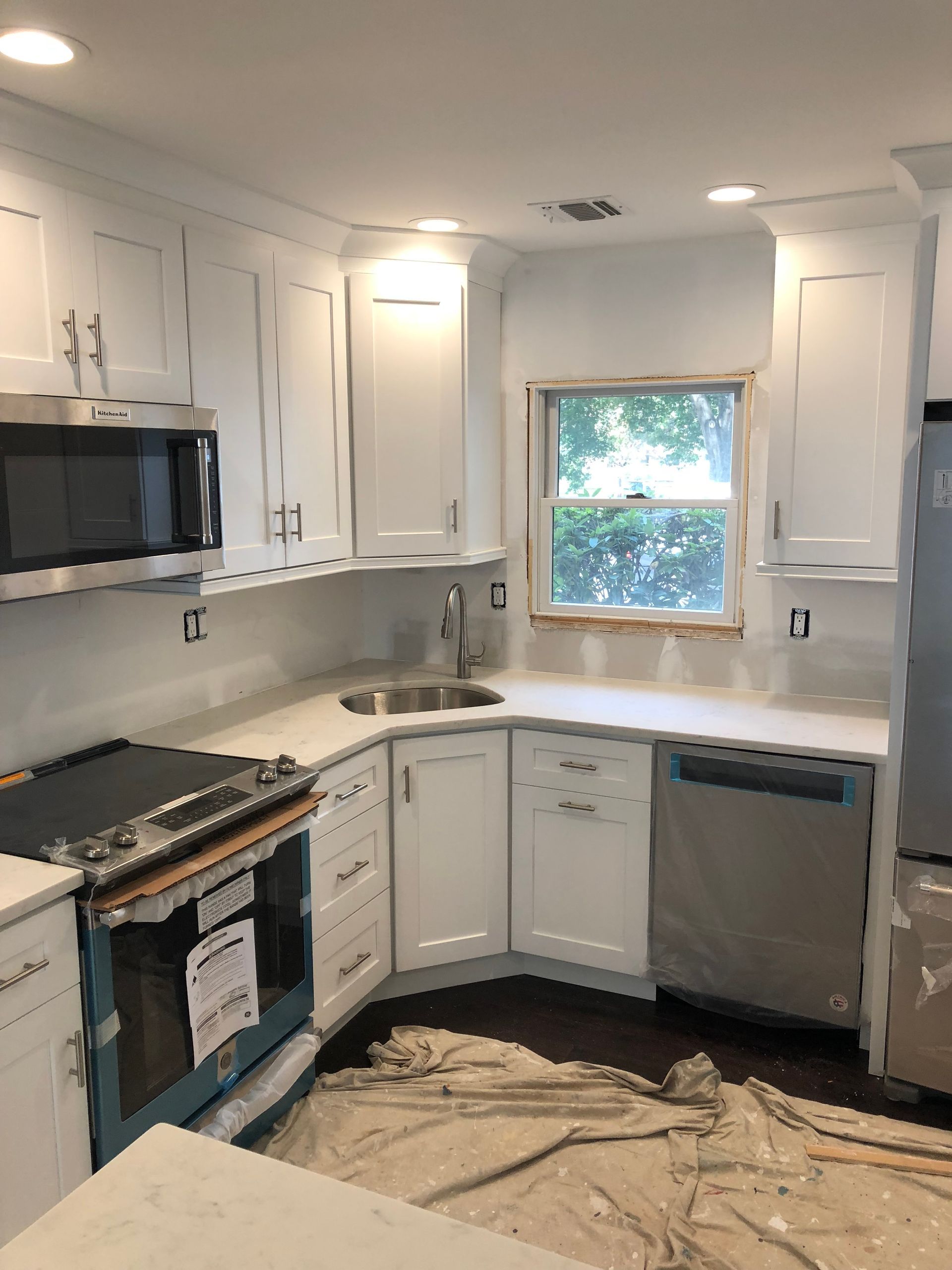 A kitchen with white cabinets , stainless steel appliances and a window.