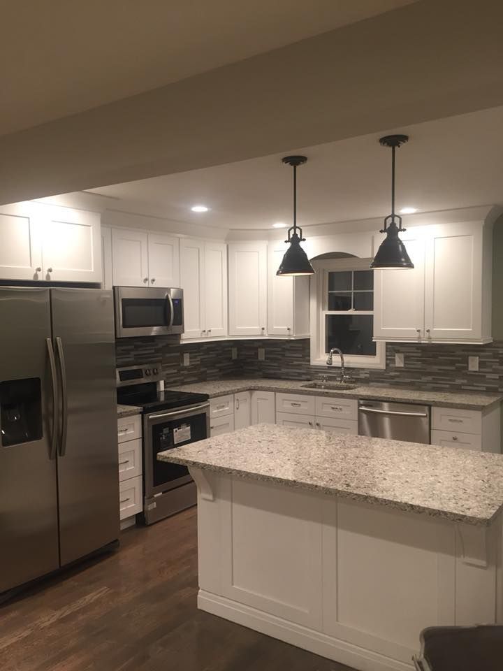 A kitchen with white cabinets , stainless steel appliances and granite counter tops.