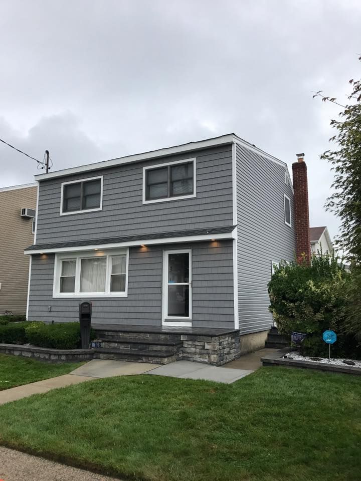 A gray house with white trim and a brick chimney