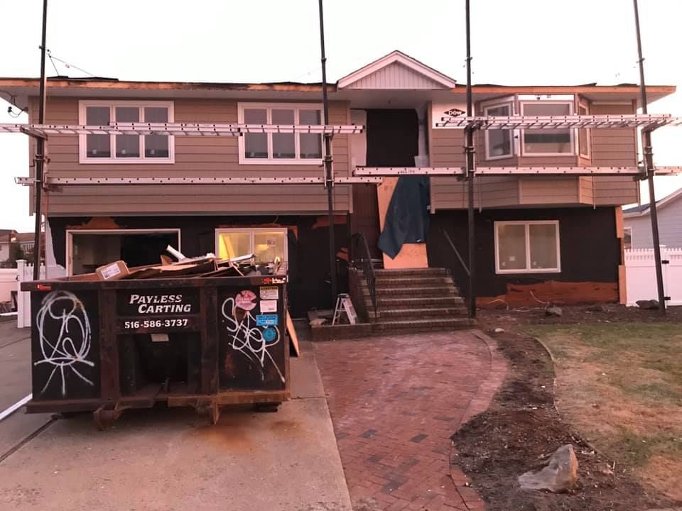 A house is being remodeled with a dumpster in front of it.