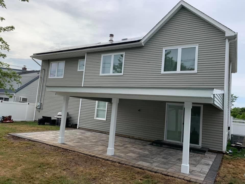 The back of a house with a patio in front of it.