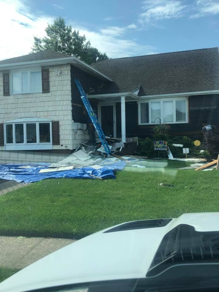 A white car is parked in front of a house that is being painted.