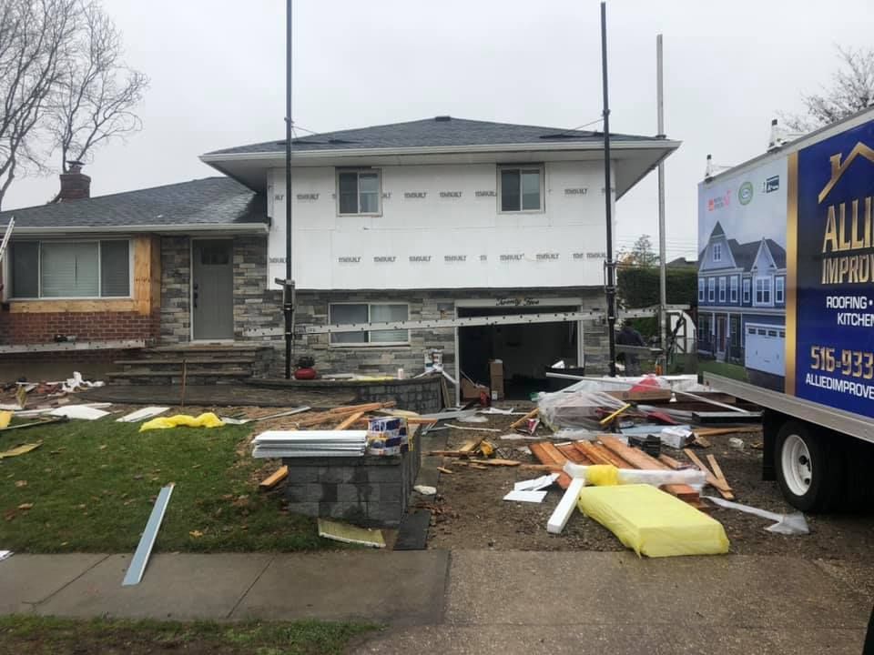 A house is being remodeled and a truck is parked in front of it.