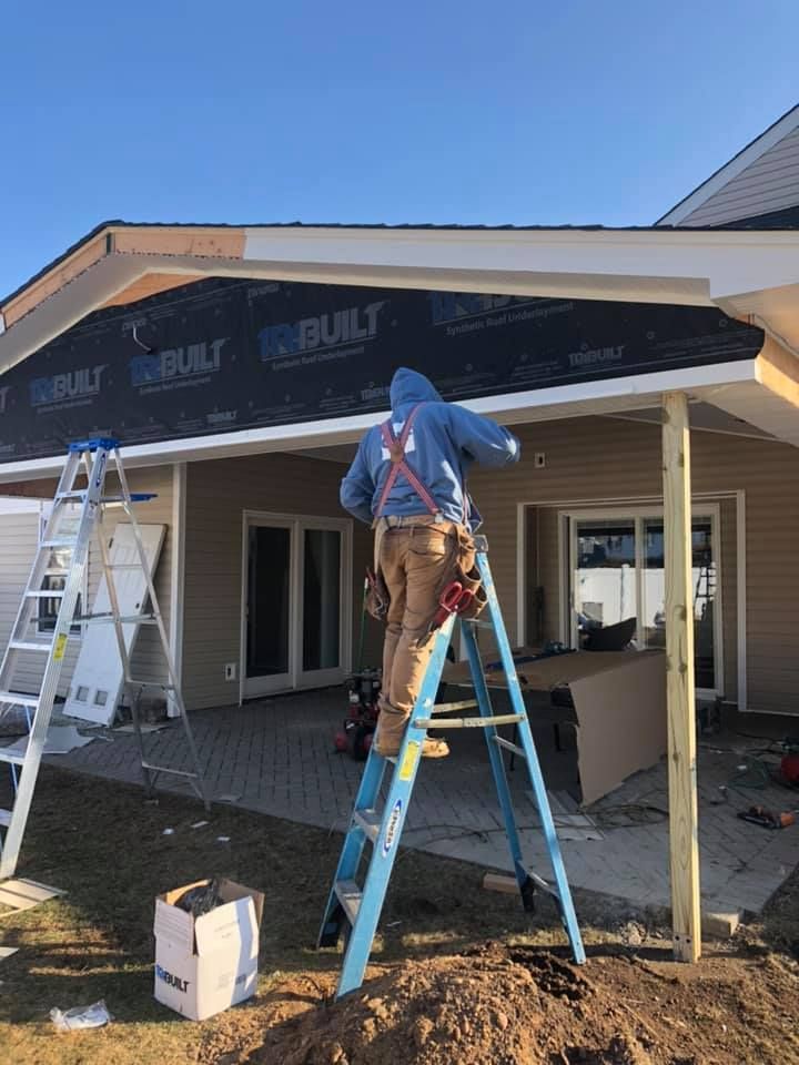 A man is standing on a ladder in front of a house.