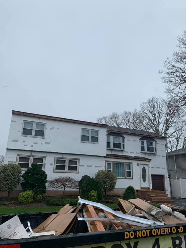 A dumpster is sitting in front of a house that is being remodeled.
