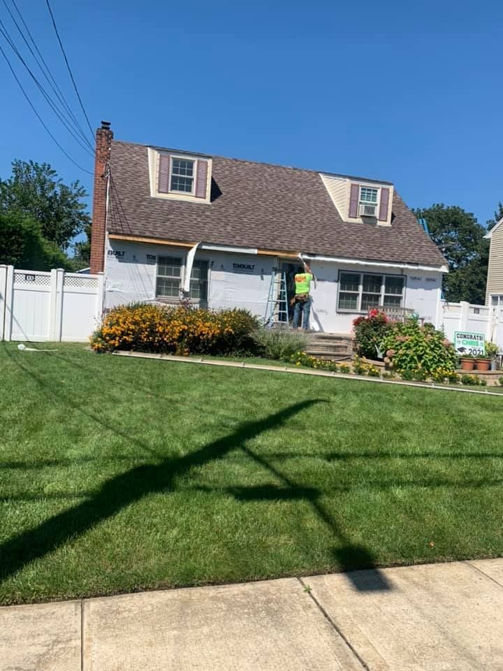 A man in a yellow vest is standing in front of a house.