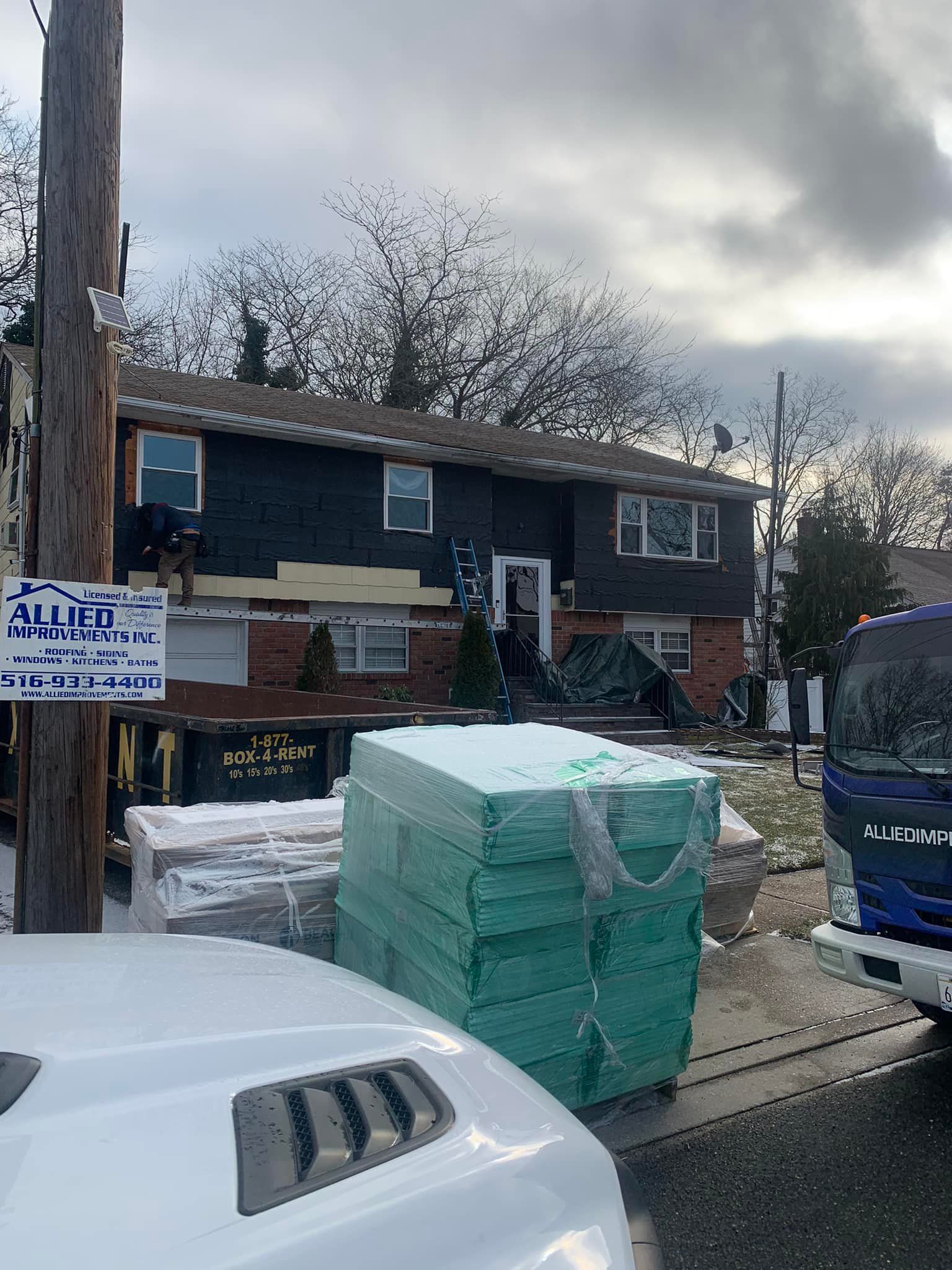 A white car is parked in front of a house that is being remodeled.