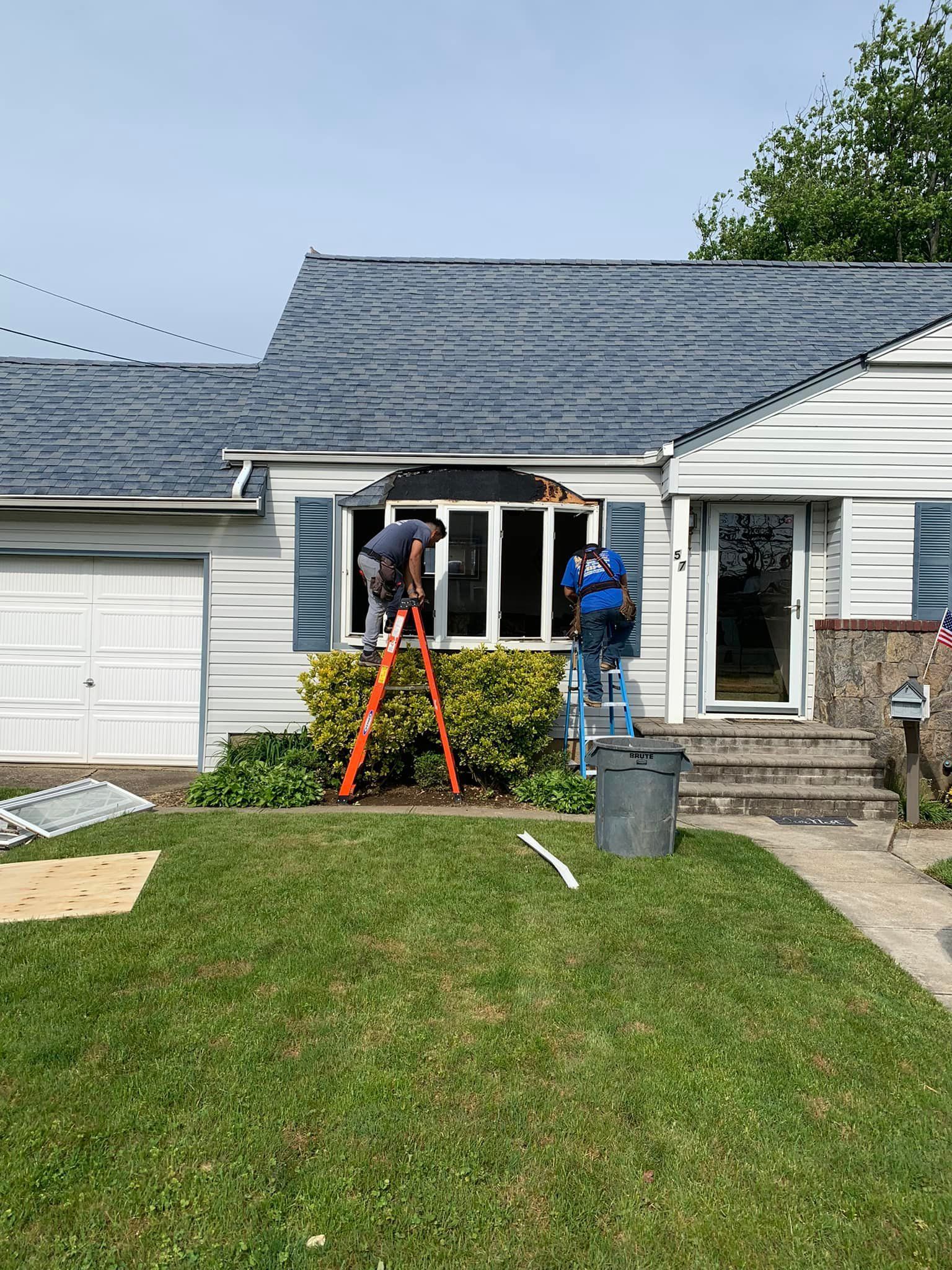 A man is standing on a ladder in front of a house.