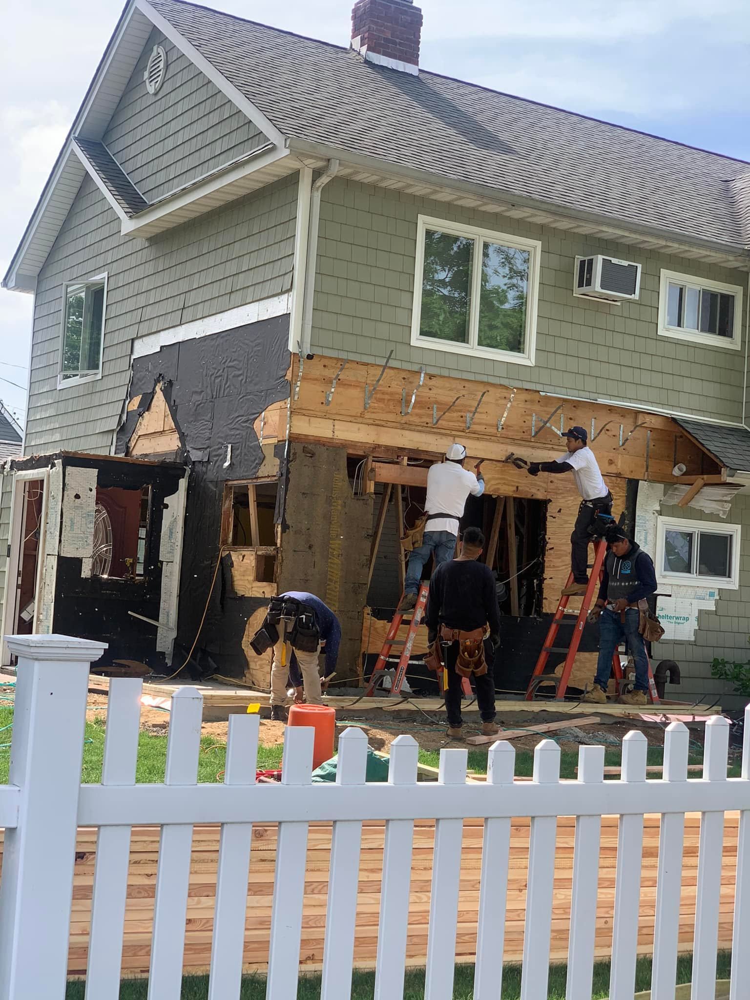 A house is being remodeled with a white picket fence in the foreground