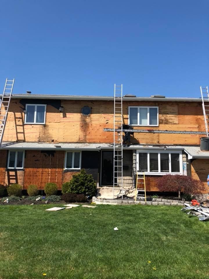 A house with a ladder on the side of it is being remodeled.