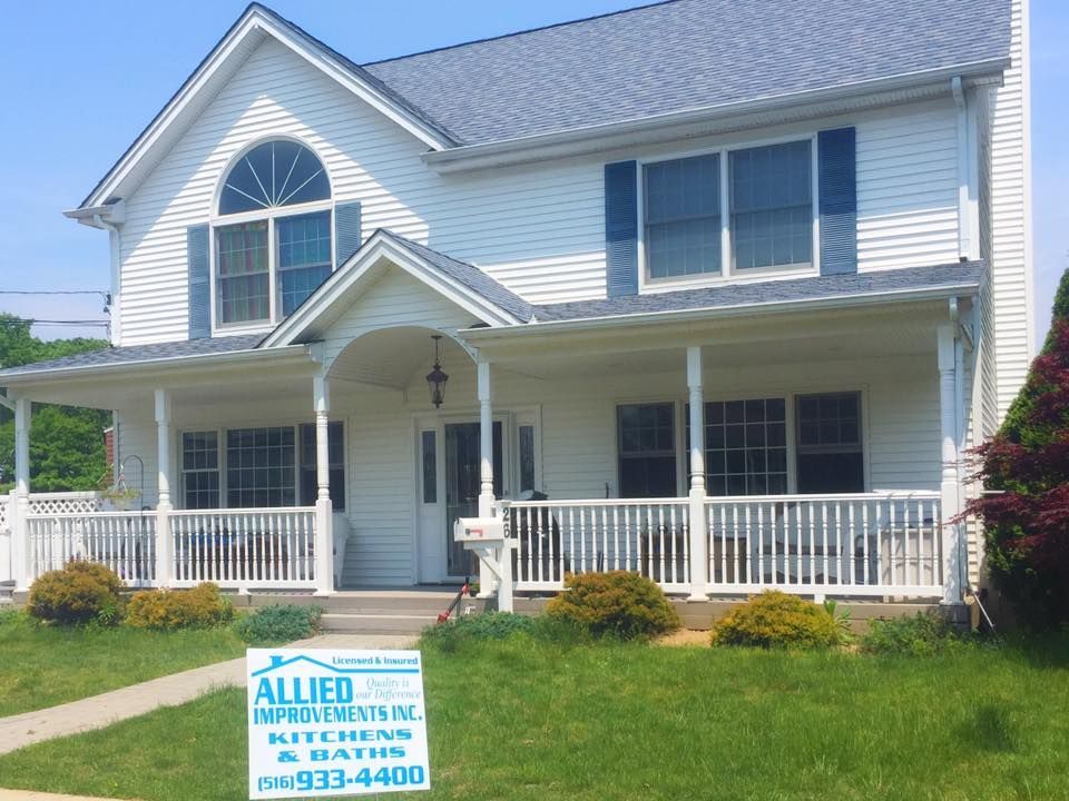 A white house with a sign that says allied improvements inc.