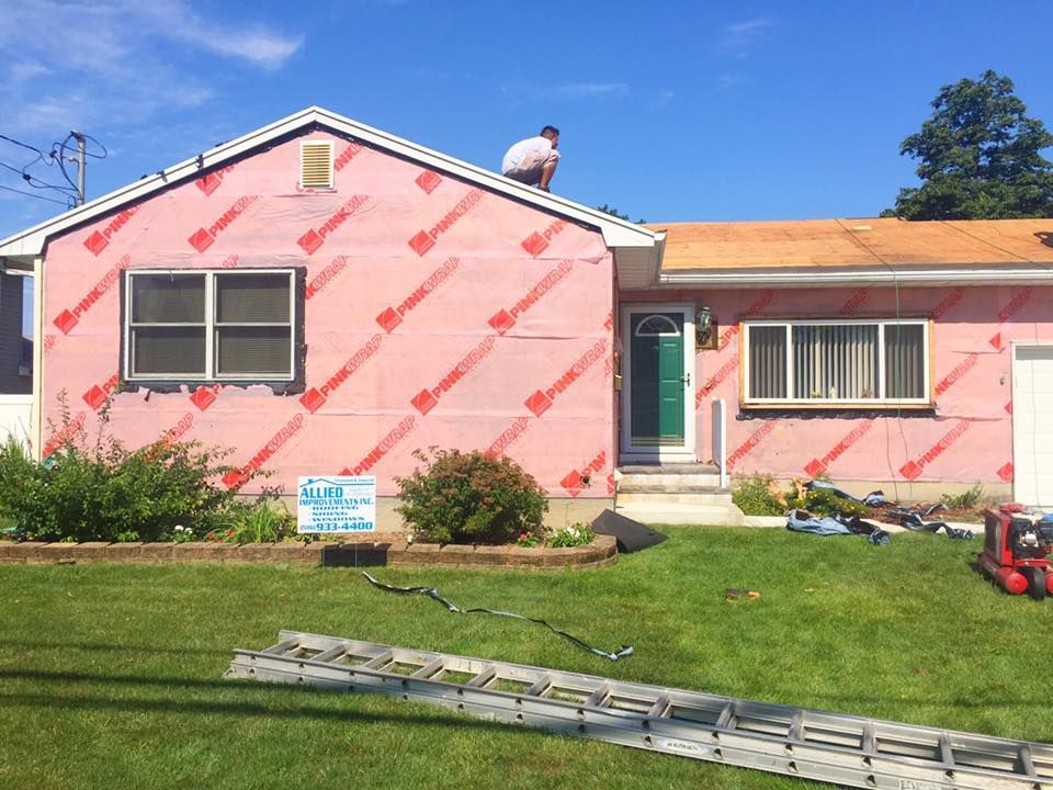 A man is standing on the roof of a pink house