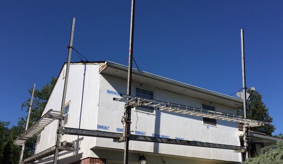 A white house with scaffolding around it and a blue sky in the background.