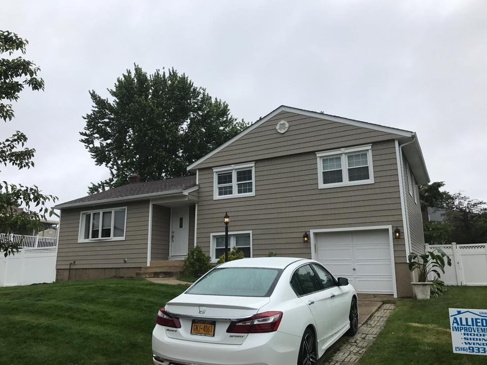 A white car is parked in front of a house.