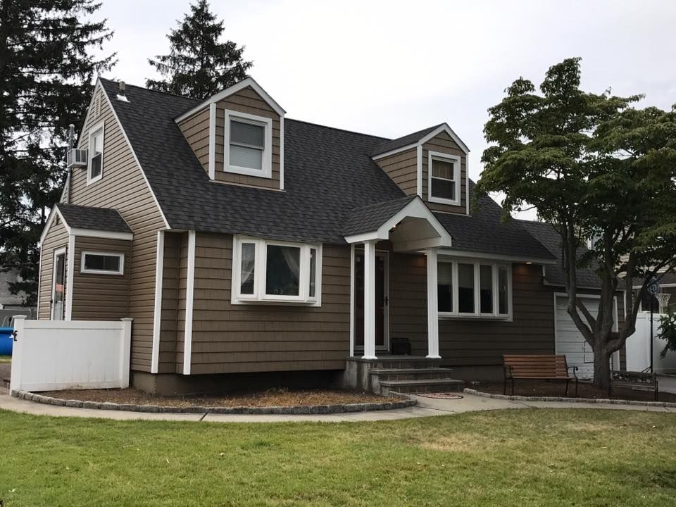 A brown house with a black roof and white trim