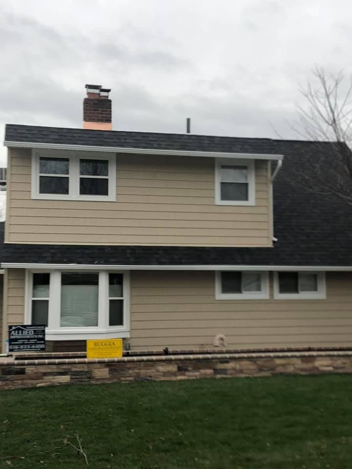 A house with a black roof and a sign in front of it.