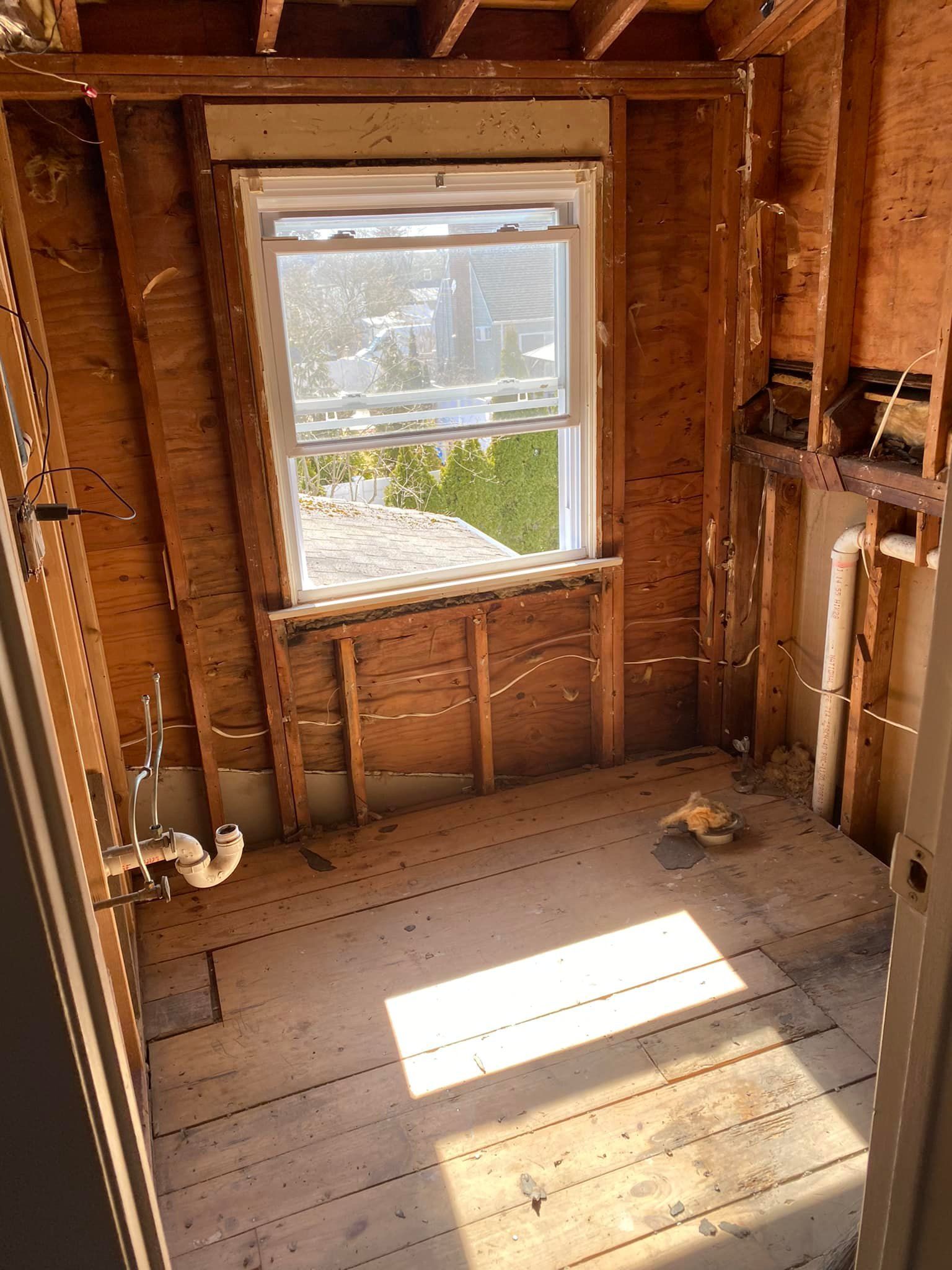 A bathroom under construction with a window and a wooden floor.