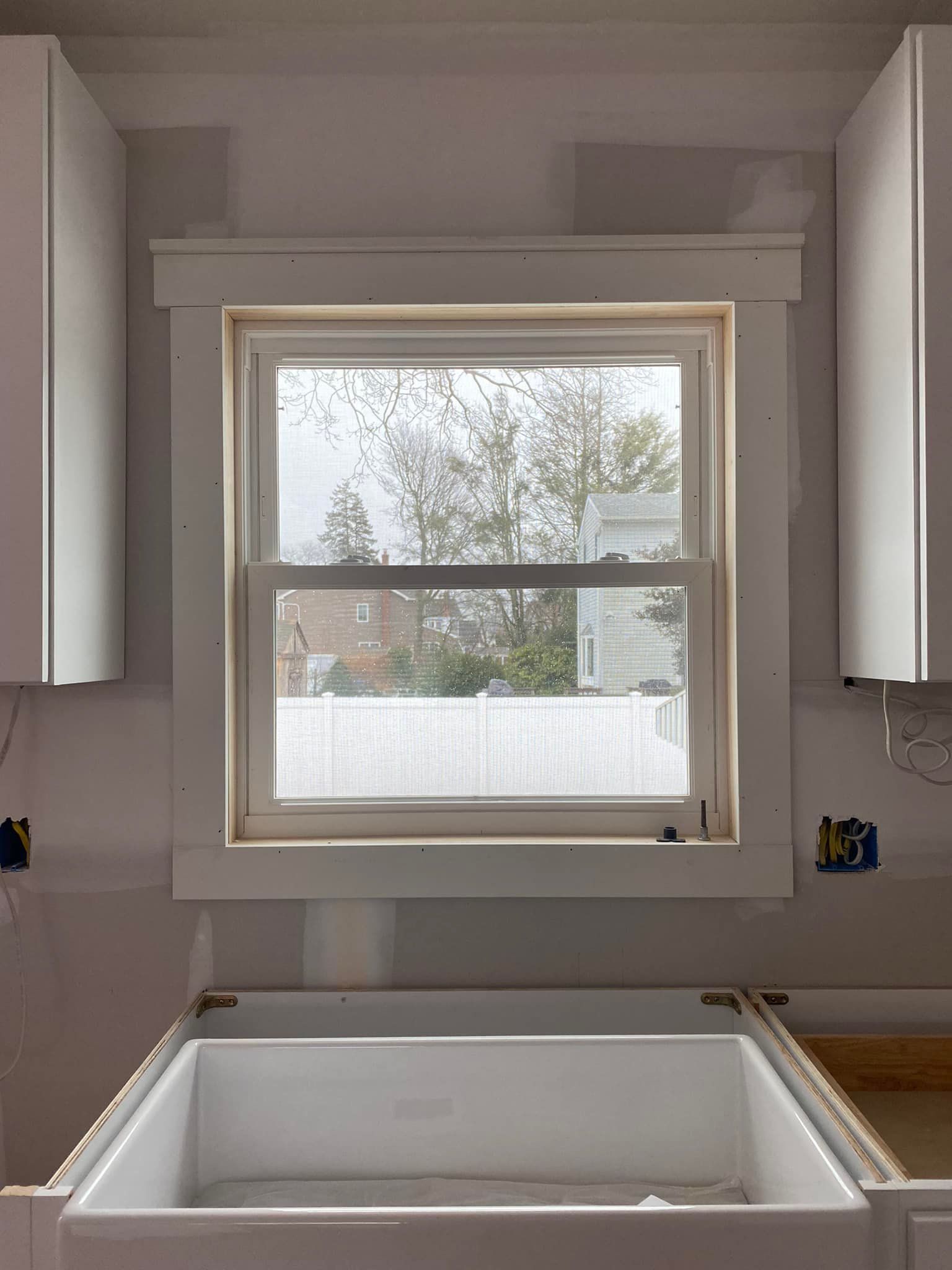 A kitchen with a sink and a window with a view of a house.