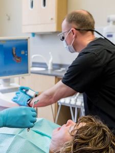 A dentist is examining a patient 's teeth in a dental office.