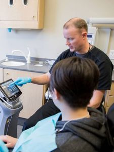A dentist is showing a tablet to a patient.
