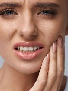 A woman is holding her mouth in pain because of a toothache.