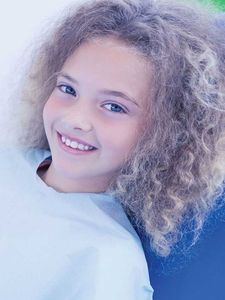 A young girl with curly hair is smiling for the camera.