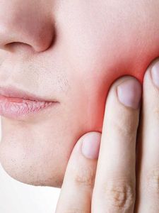 A close up of a person holding their face in pain.