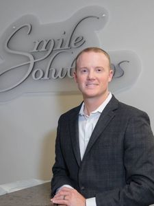 A man in a suit stands in front of a sign that says agile solutions