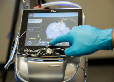 A person wearing blue gloves is pressing a button on a machine.