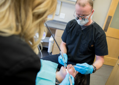 A dentist is examining a patient 's teeth in a dental office.