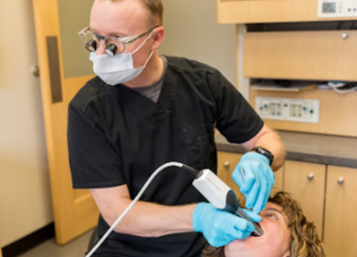 A dentist is examining a patient 's teeth in a dental office