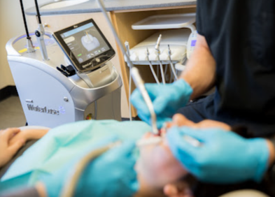 A dentist is examining a patient 's teeth in a dental office.