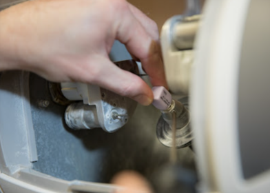 A person is opening a valve on a machine.