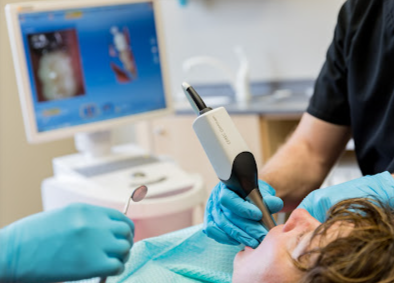 A dentist is taking a picture of a patient 's teeth.