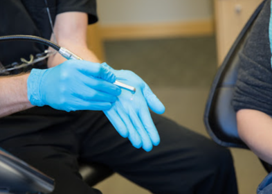 A person wearing blue gloves is holding a pen in their hand.