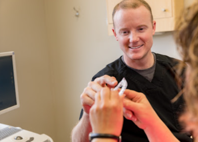 A man is examining a woman 's wrist with an ultrasound machine.
