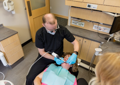 A woman is getting her teeth examined by a dentist in a dental office.