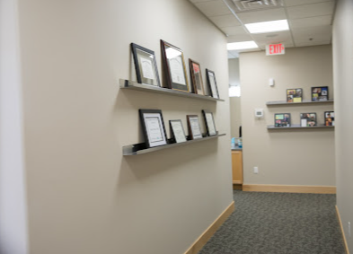 A hallway with pictures on shelves and a red exit sign