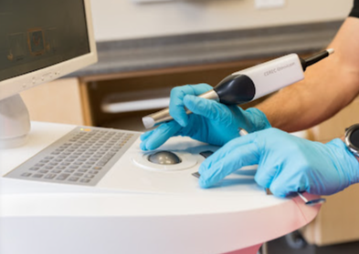 A person wearing blue gloves is working on a computer.