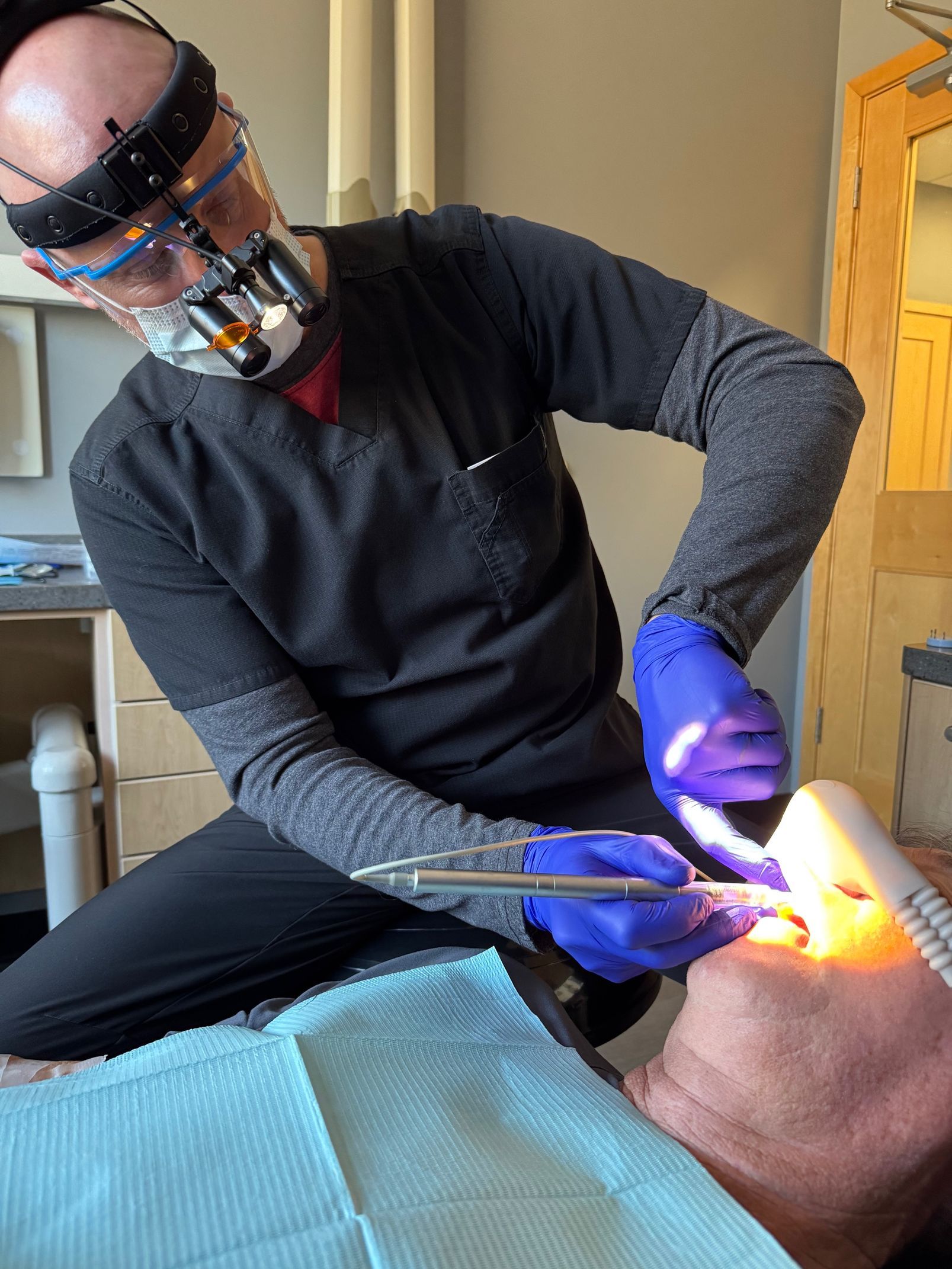 A person wearing blue gloves is using a machine to remove a tattoo