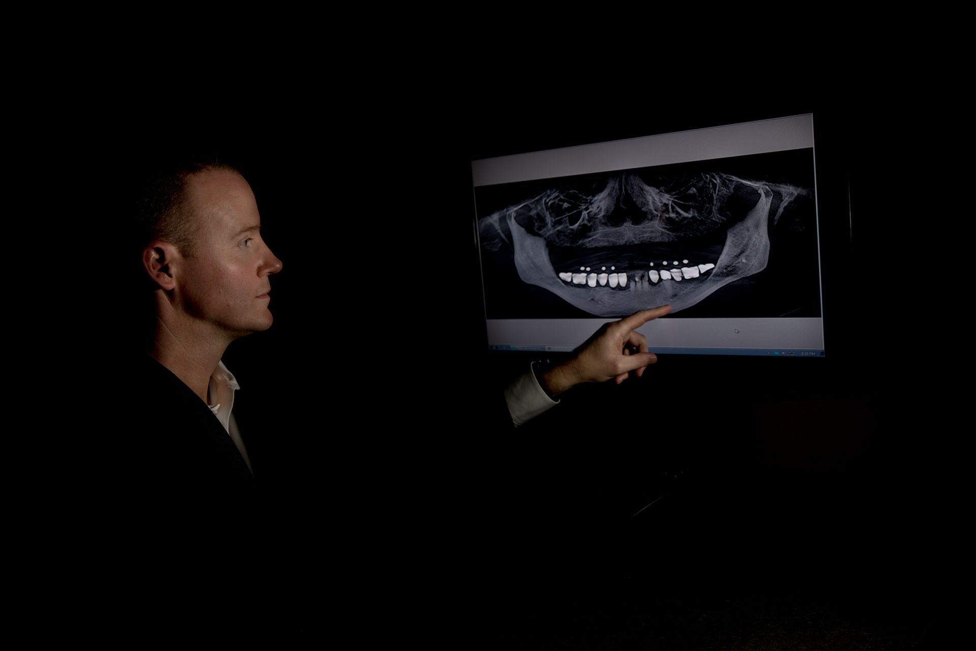 A man is pointing at a picture of a skull on a screen.