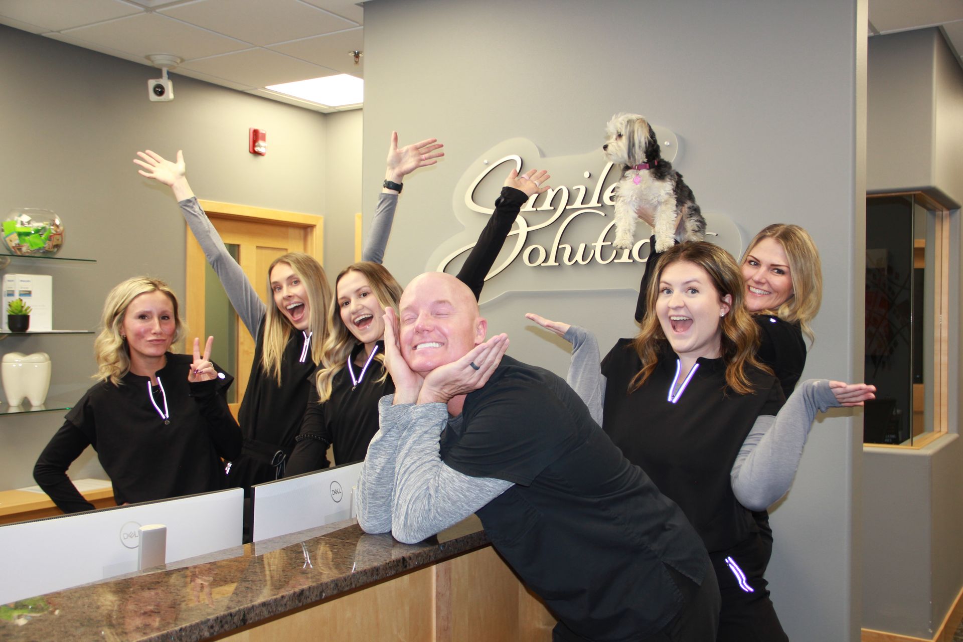 A group of people are posing for a picture in a dental office.